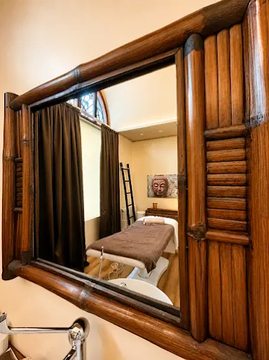 Specchio in bambù che riflette la cabina massaggi del centro